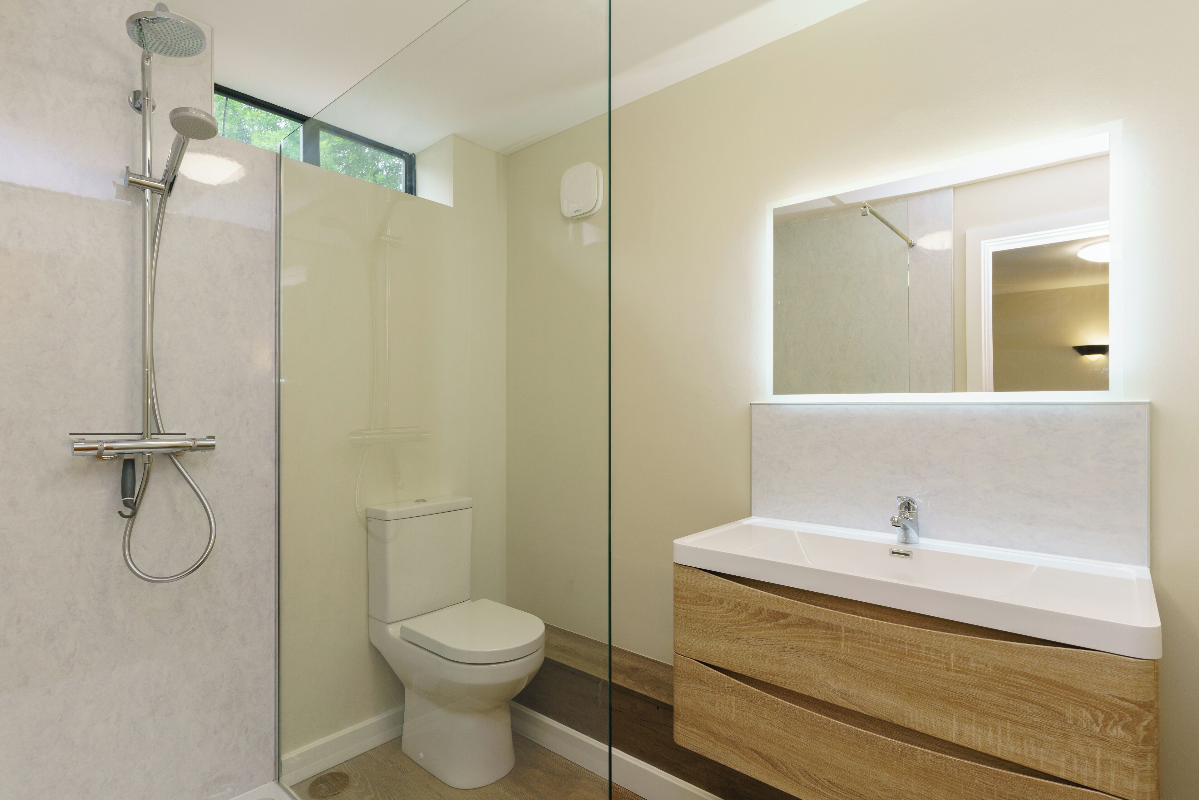 A modern bathroom with a glass shower enclosure, a toilet, and a vanity with a mirror.