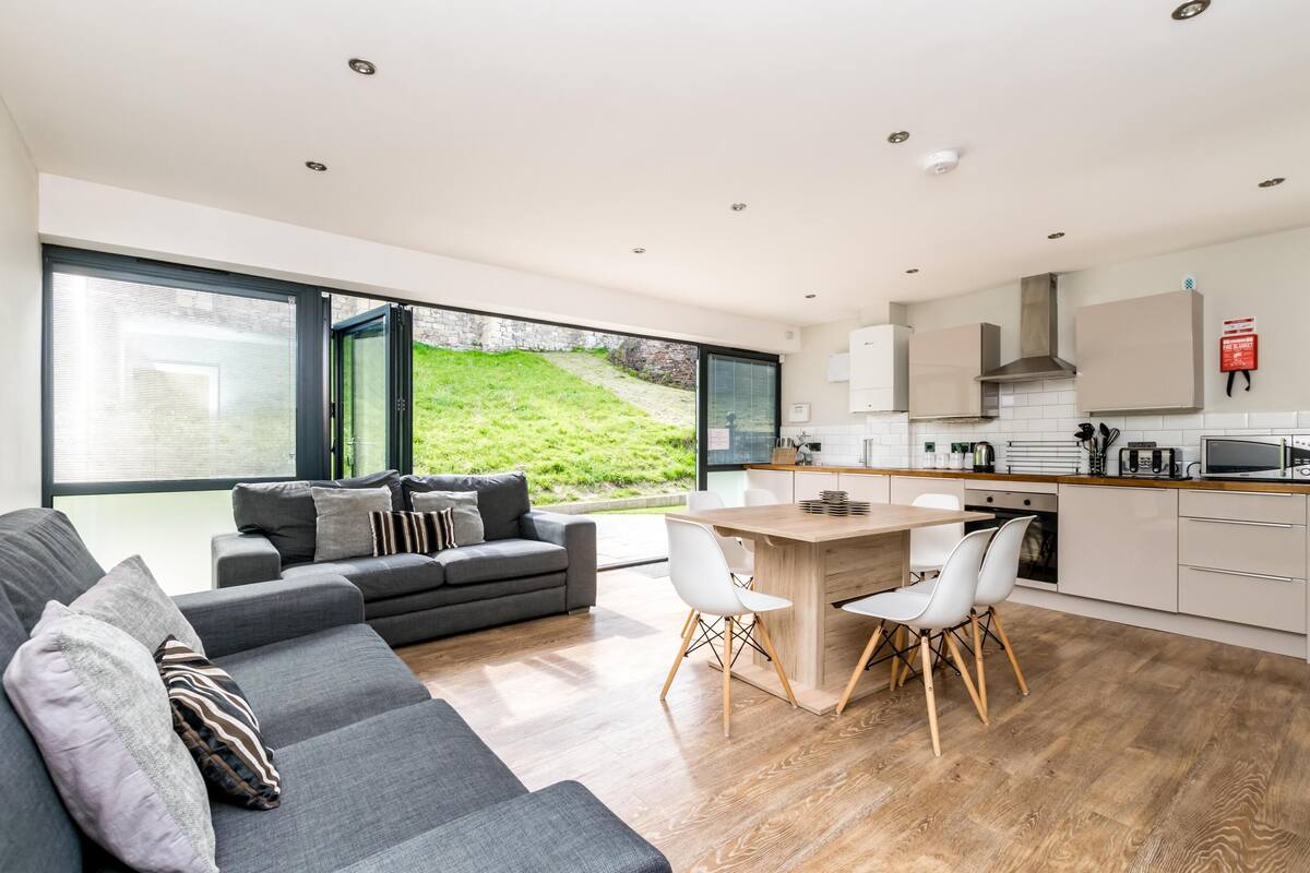 Una cocina moderna con una isla central, armarios blancos y vistas a un paisaje verde.