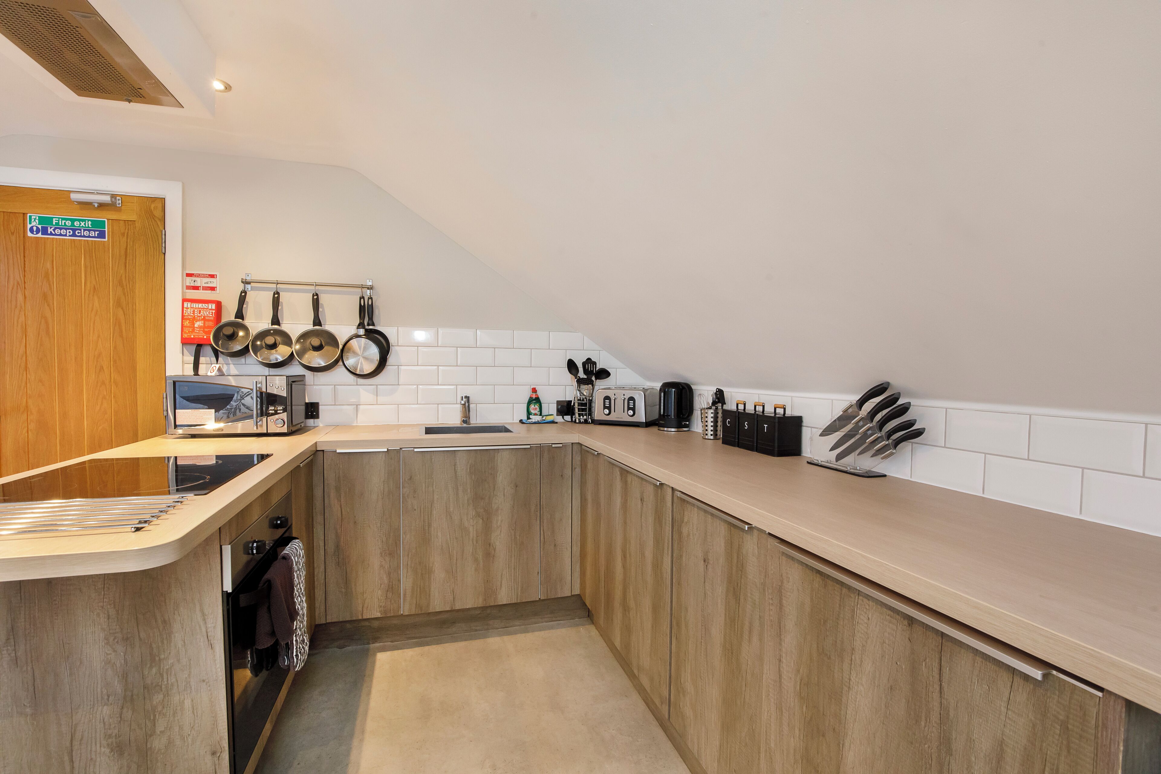 Una cocina moderna con armarios de madera, un lavamanos de acero inoxidable y una variedad de utensilios y utensilios de cocina.