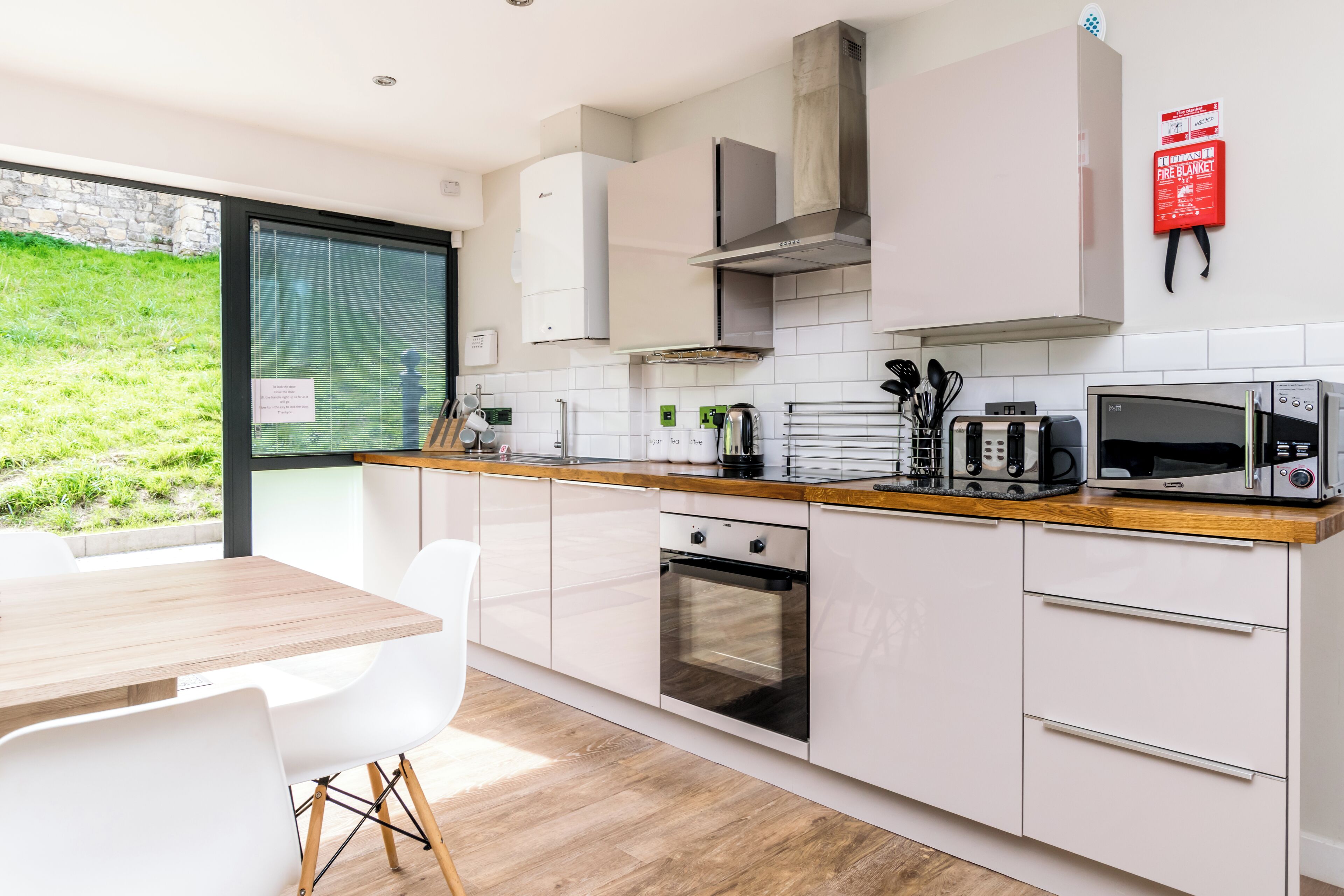 A modern kitchen with white cabinetry, a wooden countertop, and a built-in oven.