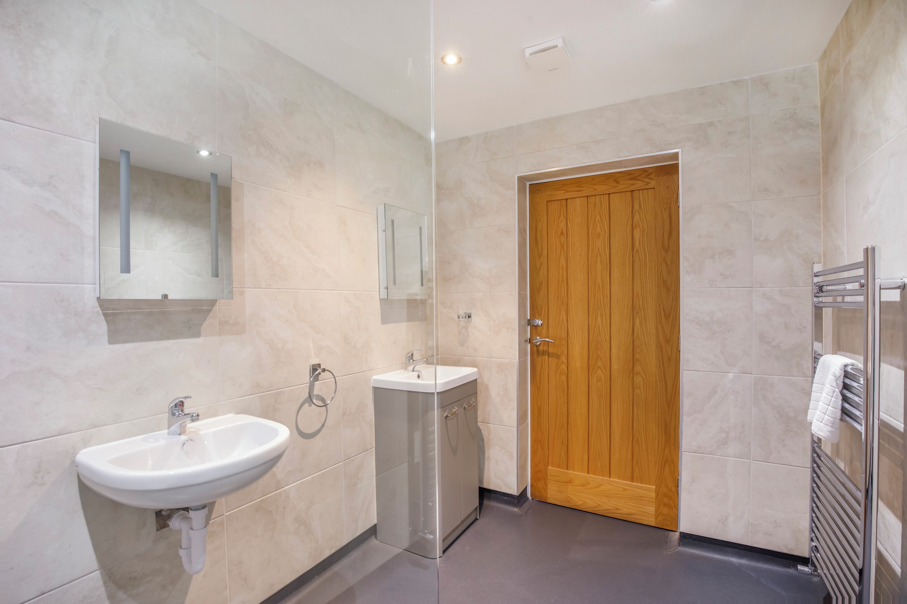A modern bathroom with a sink, mirror, and wooden door.