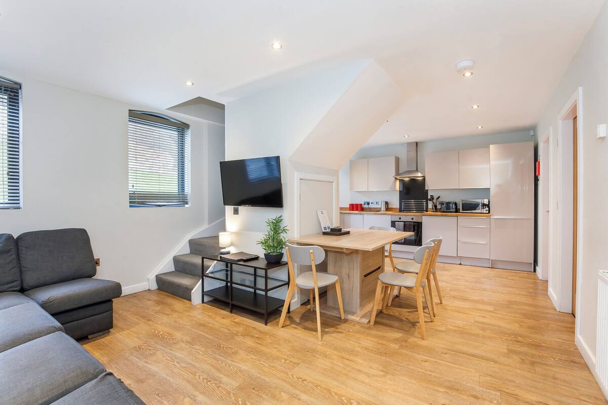 Un apartamento moderno con sala de estar, comedor, cocina y una escalera.