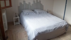 Una camera da letto con un letto, due comodini, un termosifone e un quadro appeso al muro.