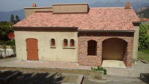 Un edificio a due piani con tetto in tegole, un ingresso ad arco in pietra e una piccola finestra con inferriata metallica.