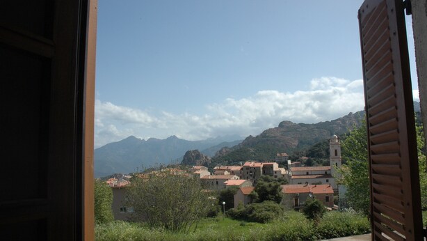 Panorama di una città con edifici e montagne sullo sfondo.