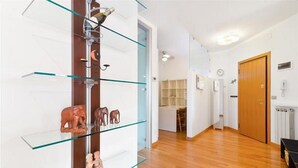 En hall med ett vitrinskåp som innehåller små figurer, en trädörr och ett element.