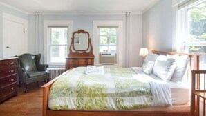 Une chambre à coucher avec un lit, une commode, une chaise et un miroir.