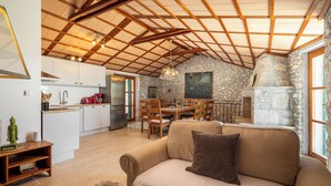 Amplia sala de estar con techo de madera, pared de piedra y comedor con muebles de madera.