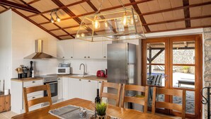 Una cocina moderna con gabinetes blancos, electrodomésticos de acero inoxidable y una mesa de comedor de madera con sillas.