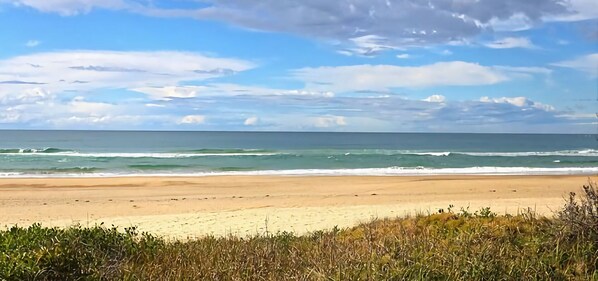A beach with a wide sandy shore and ocean waves. - Tee Jays is an air-conditioned ground floor two bedroom unit, central to Sawtell (Sawtell)
