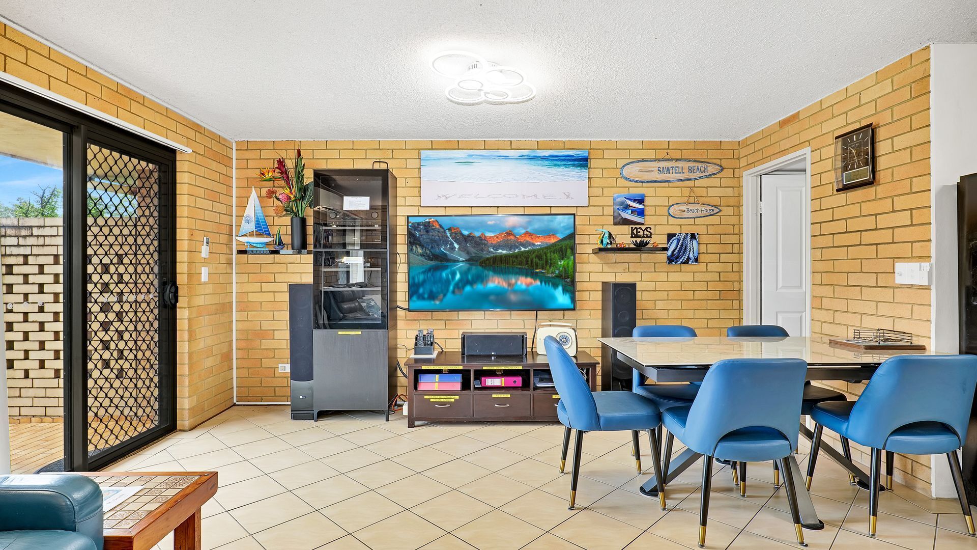 A dining area with a brick wall, a large painting, and a clock.