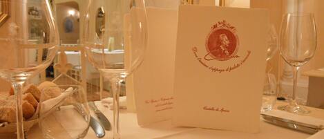 A table set with wine glasses, a menu, and a bowl of bread.