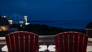 Two red chairs with a view of the ocean and a house in the background. - Dog Friendly - Sound View Home on private harbor. Amazing Sunsets-Fishing-Dock (Salvo)
