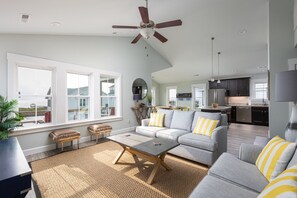 A spacious living room with a grey sofa, a coffee table, and a ceiling fan. - Dog Friendly - Sound View Home on private harbor. Amazing Sunsets-Fishing-Dock (Salvo)