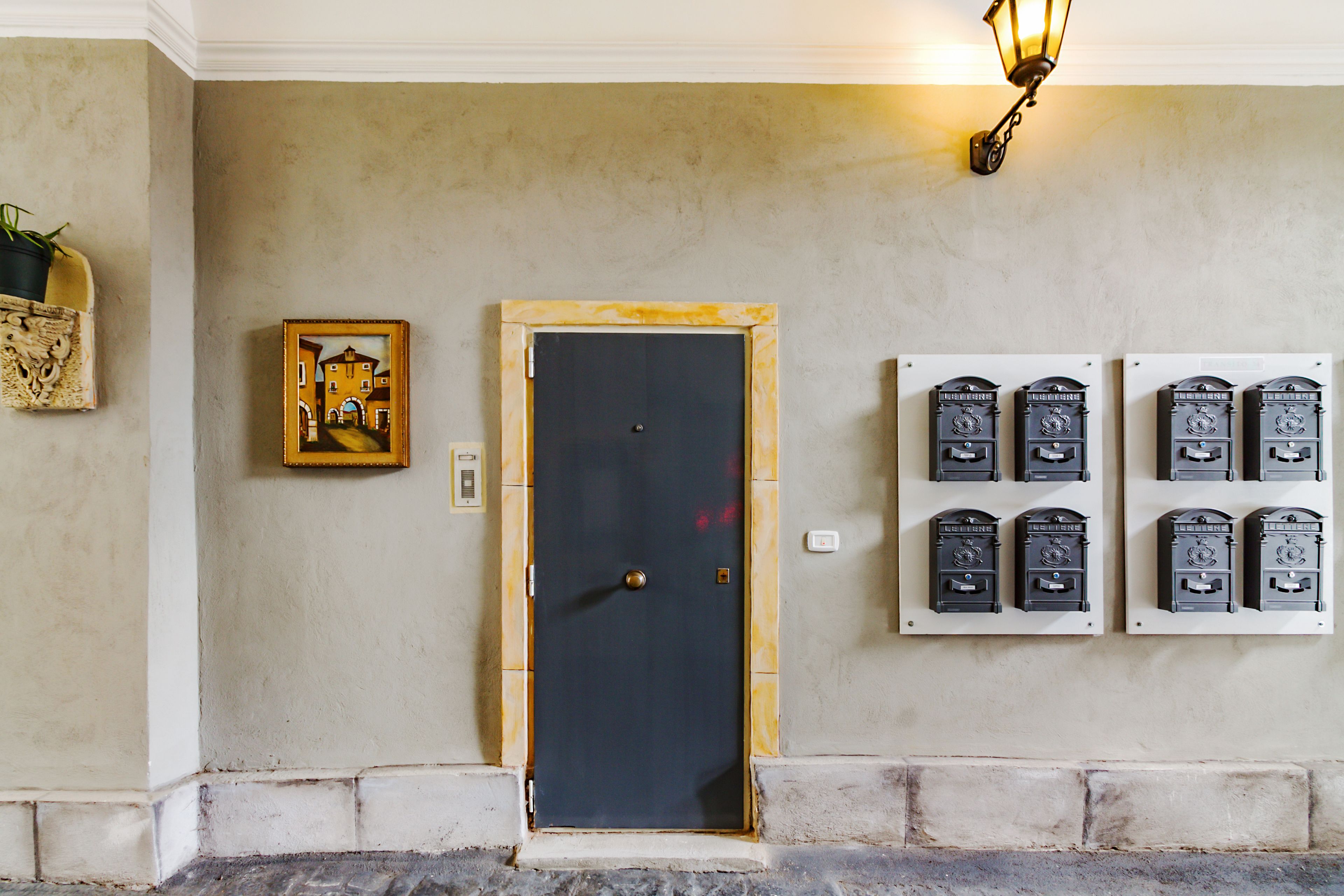Une porte avec une poignée en laiton, un tableau encadré accroché au mur et un luminaire fixé au mur.