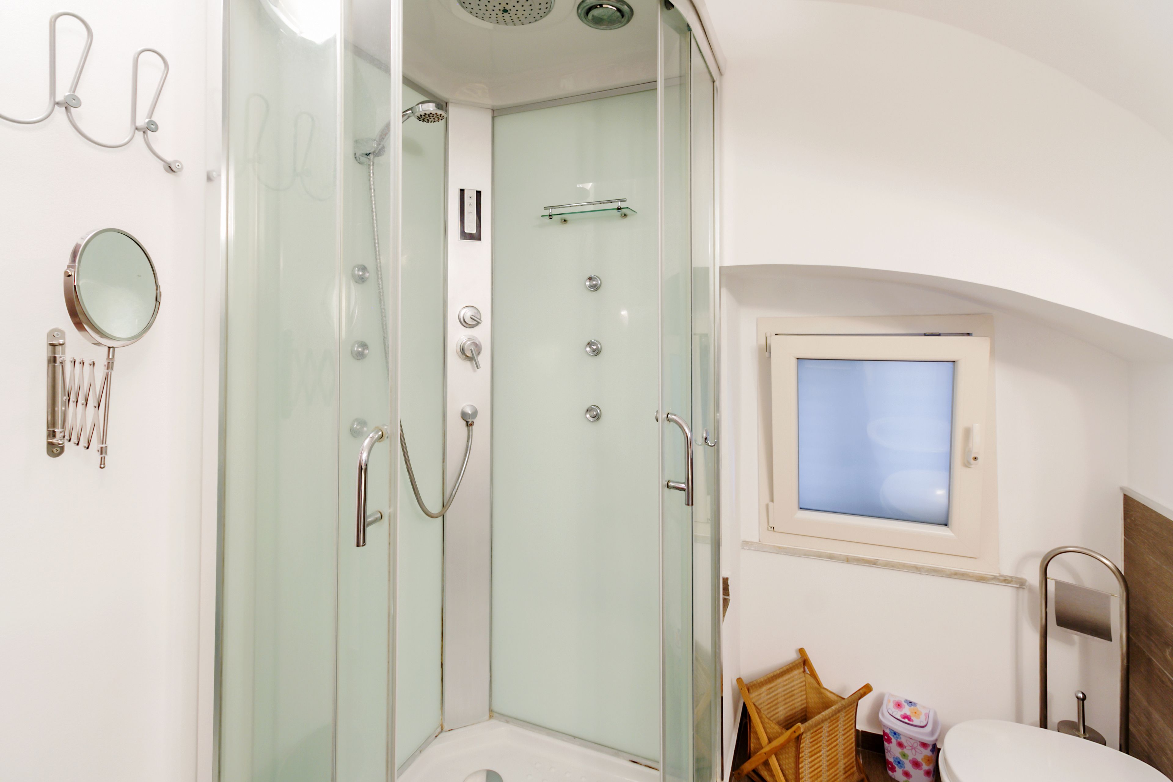 Een moderne badkamer met een douchecabine van glas, een toilet en een klein raam.