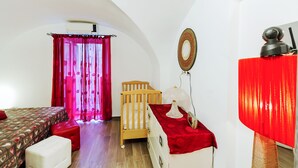 Un dormitorio con cama, cuna, lámpara roja y espejo en la pared.
