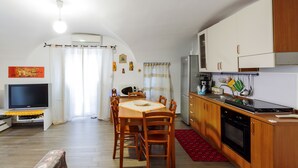 Un espacio habitable compacto con comedor, kitchenette y televisor.
