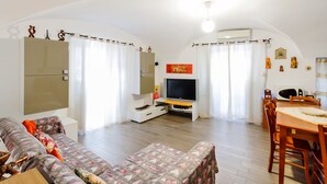 Una sala de estar con sofá, televisor y mesa de comedor.