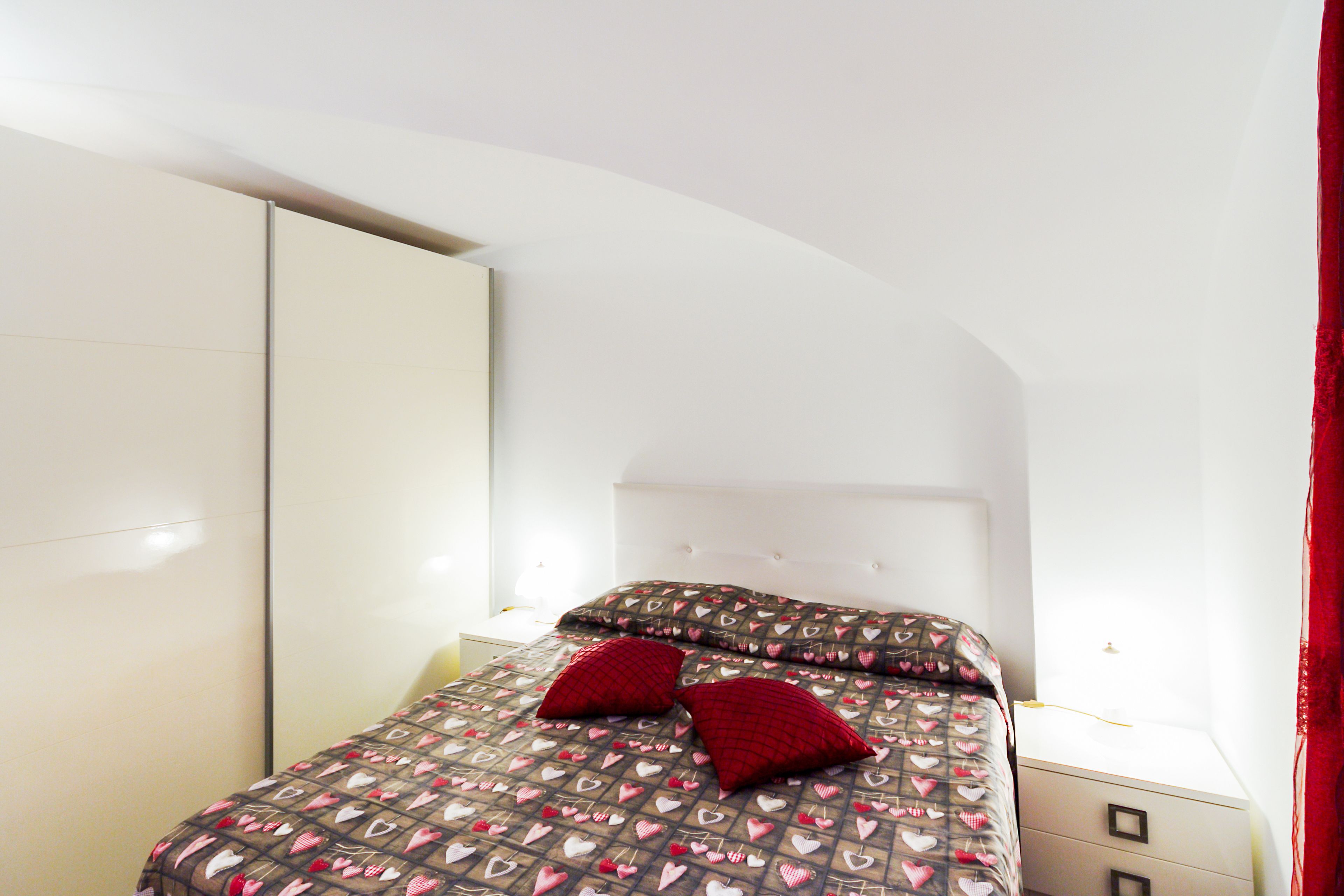 A bedroom with a bed, a wardrobe, and a nightstand.