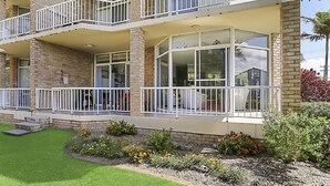 Un edificio de varios pisos con balcones, ventanas amplias y un jardín ajardinado.