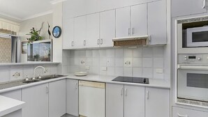 Una cocina moderna con armarios blancos, horno integrado y microondas.