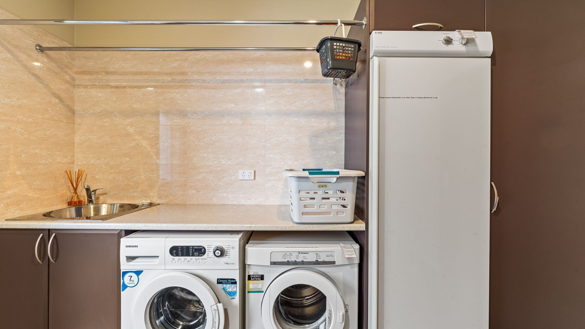 Un espace buanderie compact comprenant un lave-linge, un sèche-linge et un petit évier.