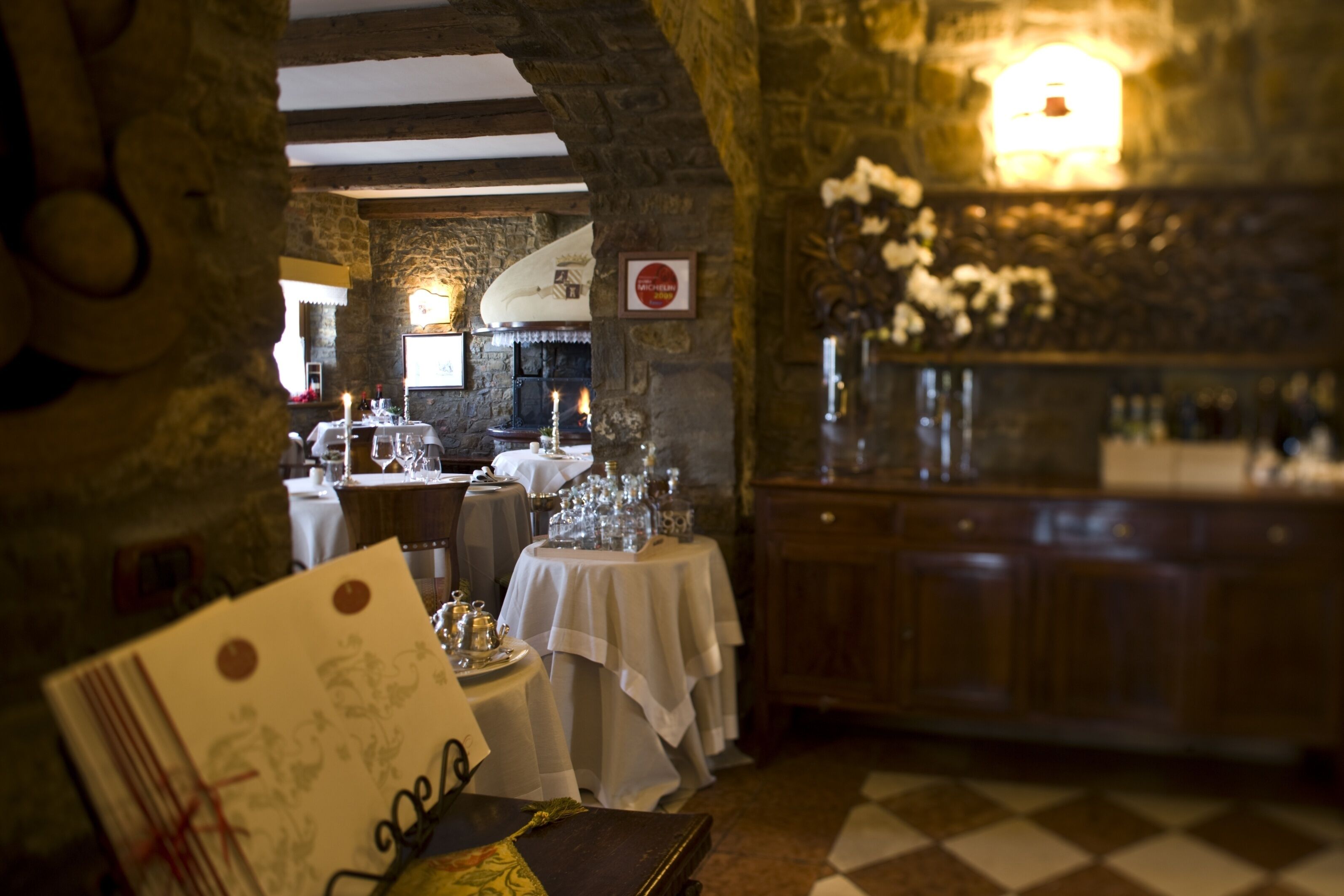 A restaurant interior with stone walls, a checkered floor, and tables set for dining.
