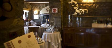A restaurant interior with stone walls, a checkered floor, and tables set for dining.