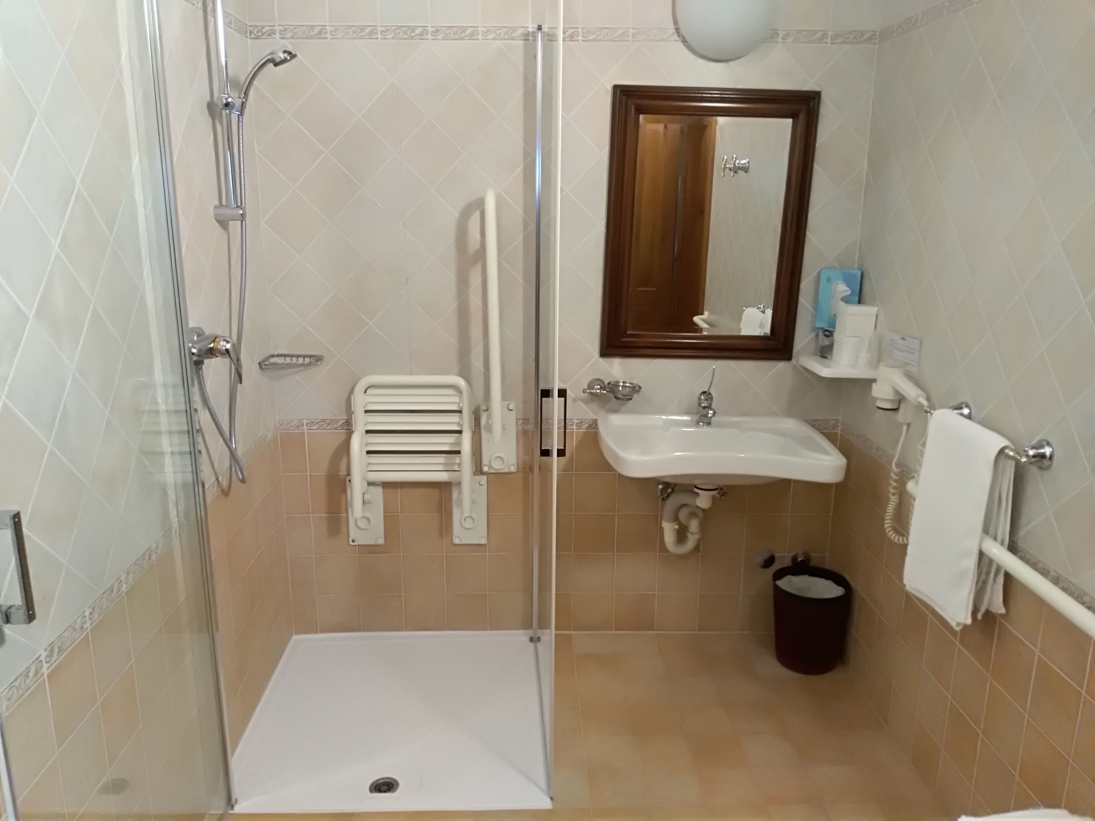 A bathroom with a shower, a sink, a toilet, a mirror, and a towel rack.