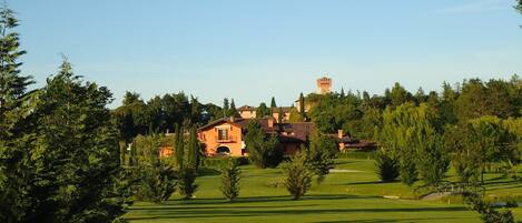 A golf course with a large house and a tower in the background.