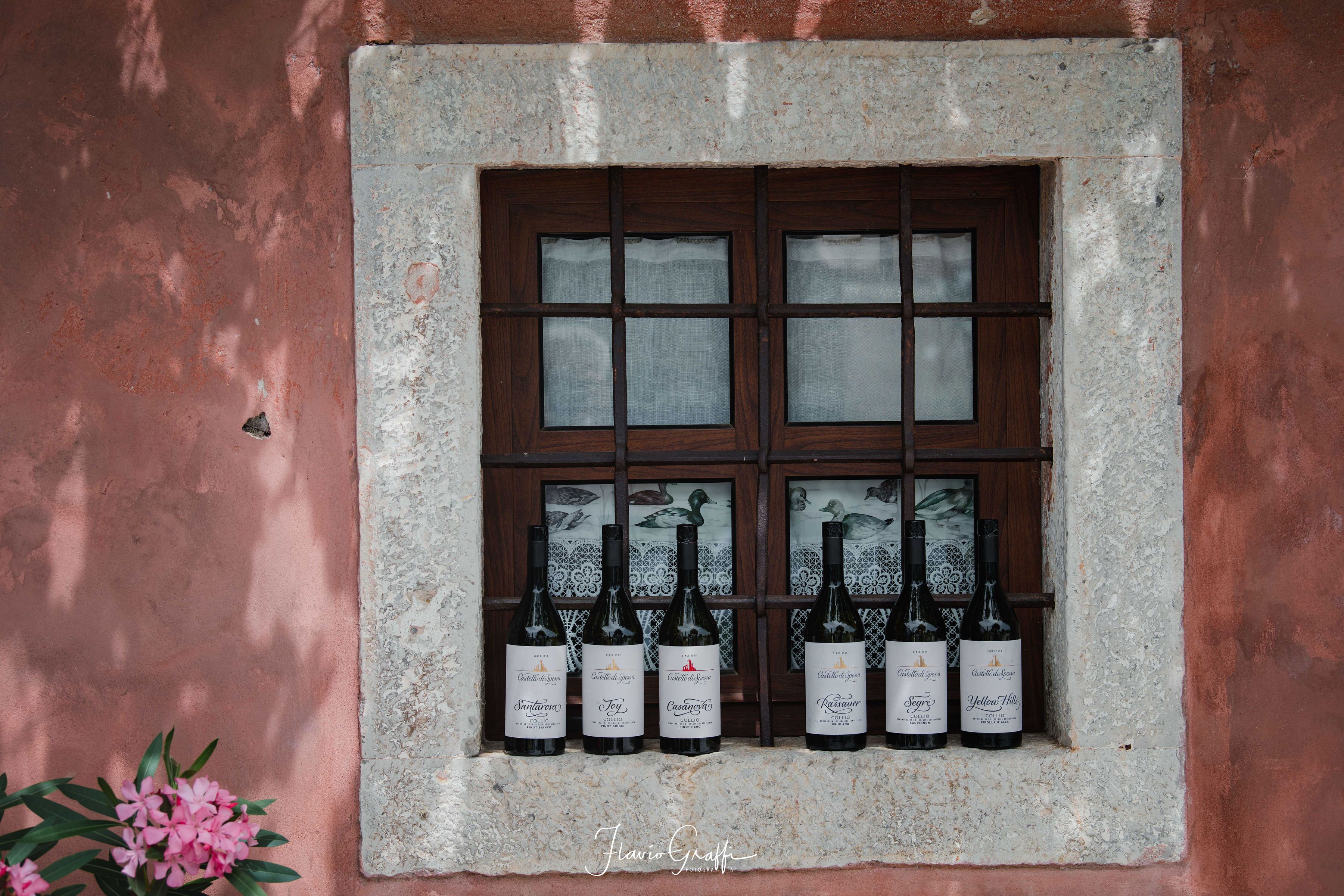 Una ventana con seis botellas de vino dispuestas en dos filas.
