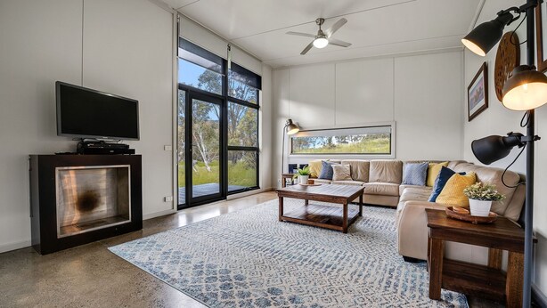 Ein modernes Wohnzimmer mit Flachbildfernseher, Sofa, Couchtisch und einem großen Fenster mit Blick ins Freie.
