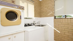 Un área de lavandería compacta con lavadora, secadora y lavabo.