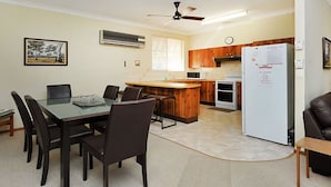Cocina compacta con zona de comedor, refrigerador y un reloj en la pared.