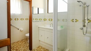 Une salle de bain équipée de toilettes, d’un lavabo et d’une douche.