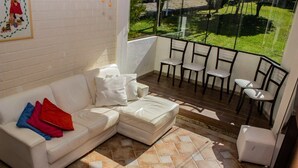 Um espaço de estar acolhedor com um sofá branco, uma mesa pequena e cadeiras.