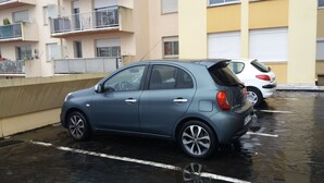 Een parkeerplaats met een blauwe auto en een witte auto.