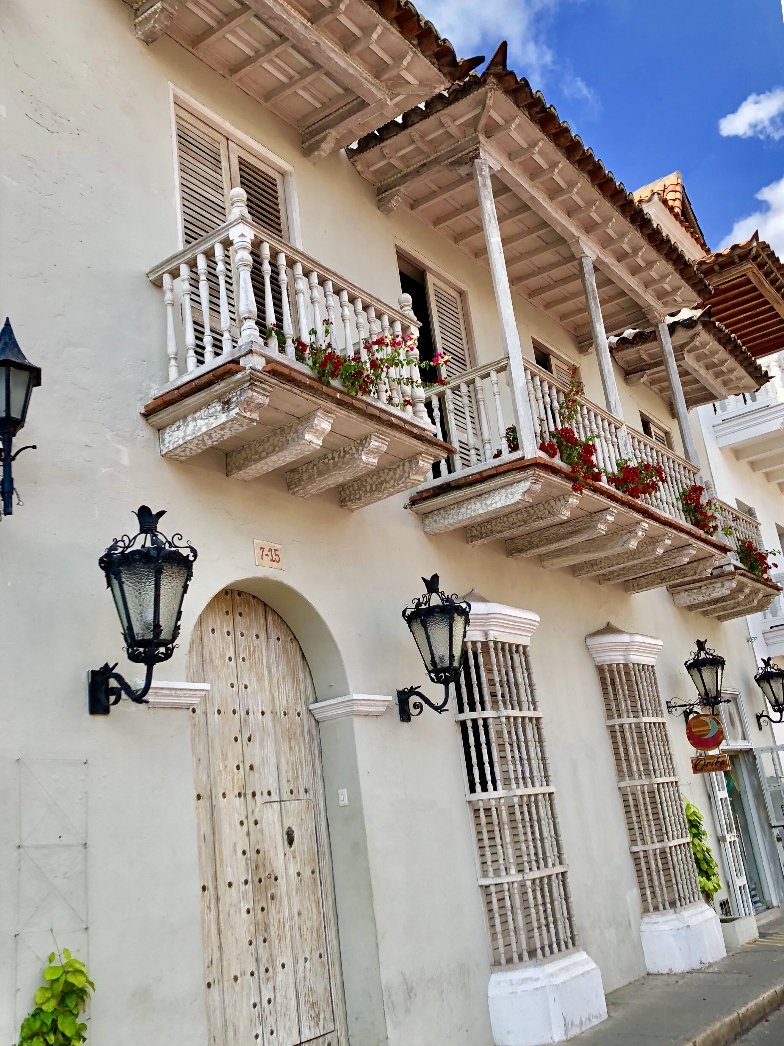 A building with white walls, multiple balconies with white railings, and a tiled roof.