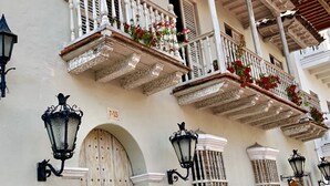 A building with white walls, multiple balconies with white railings, and a tiled roof.