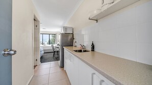 Eine moderne Küche mit weißen Schränken, einem Edelstahlkühlschrank und einer Arbeitsplatte mit Spüle und Seifenspender.