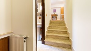 Eine Treppe führt zu einem Badezimmer mit Heizkörper und Waschbecken.