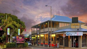 A two-story building with a balcony, a sign reading "Fish Tales," and a storefront with a sign for "12D Studios." - Ocean Sands 5 is a fully furnished two bedroom unit located on the first floor, next to the beach. (Sawtell)