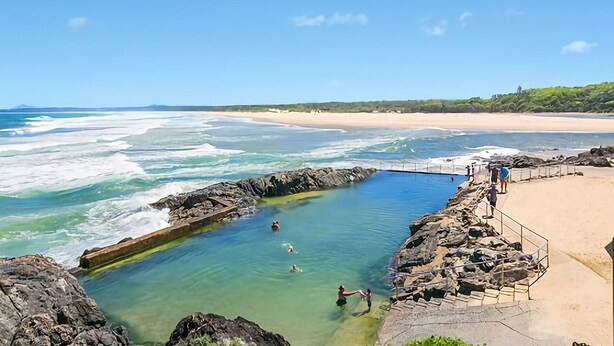 A coastal swimming area with clear water, rocky edges, and a sandy beach in the background. - Ocean Sands 5 is a fully furnished two bedroom unit located on the first floor, next to the beach. (Sawtell)