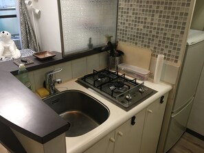 A compact kitchen with a gas stove, sink, and a refrigerator.