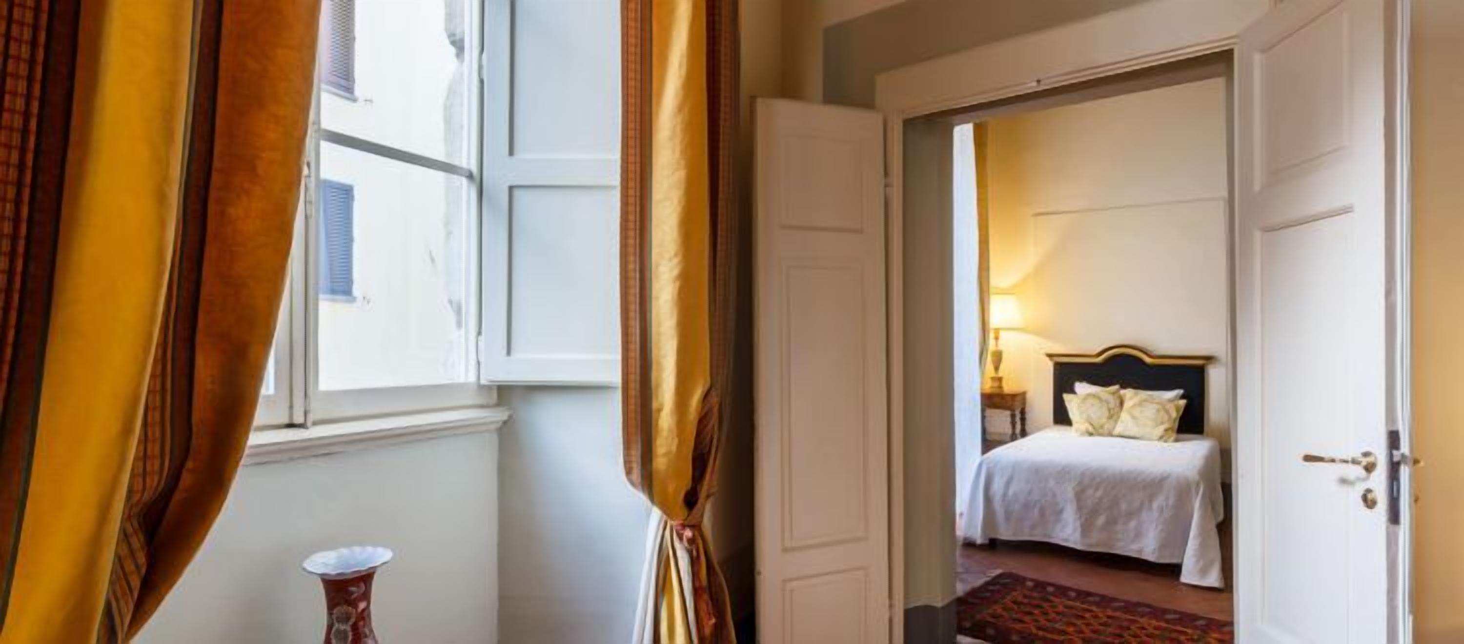A hotel room with a bed, a bedside table, and a lamp.