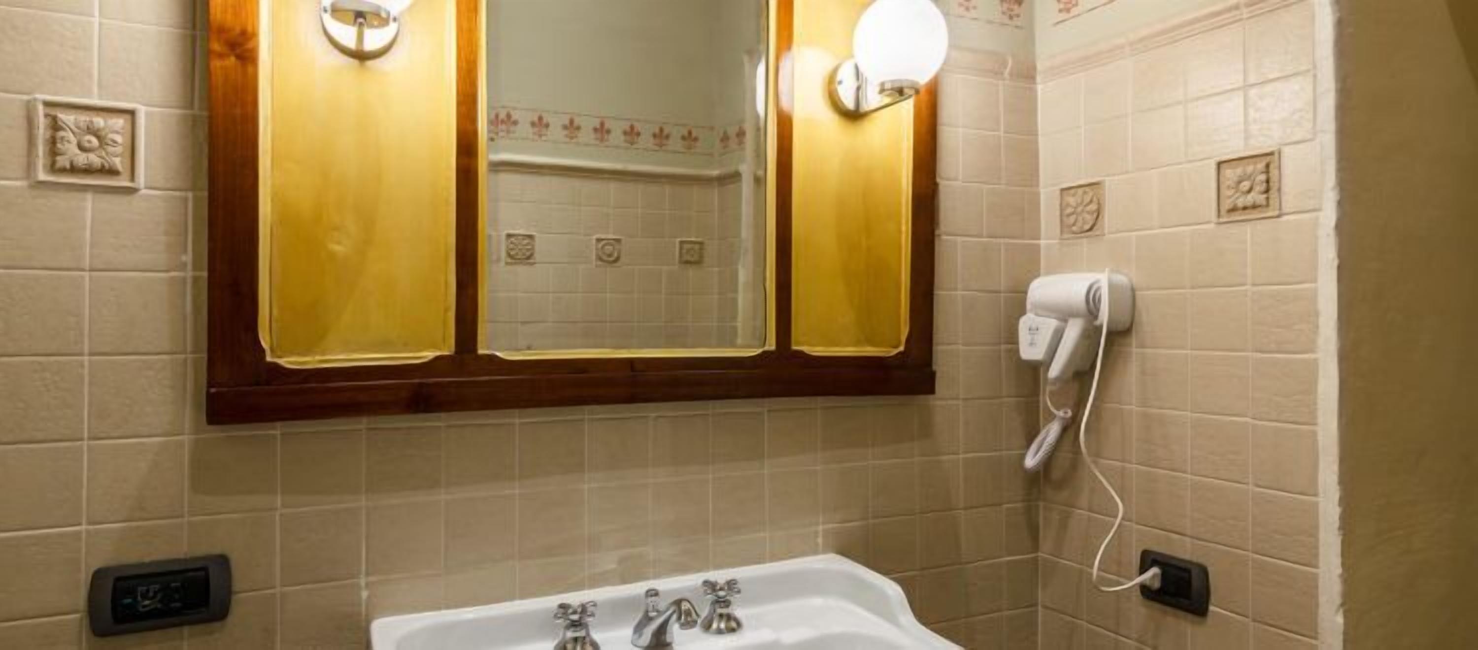 A bathroom with a sink, mirror, and towel dispenser.