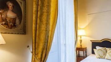 A hotel room with a bed, a nightstand, a lamp, a painting on the wall, and curtains.
