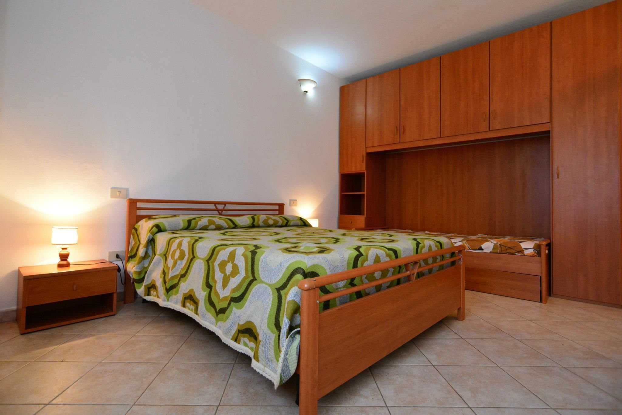 Une chambre à coucher avec un lit en bois, une table de chevet, une armoire et une lampe de chevet.