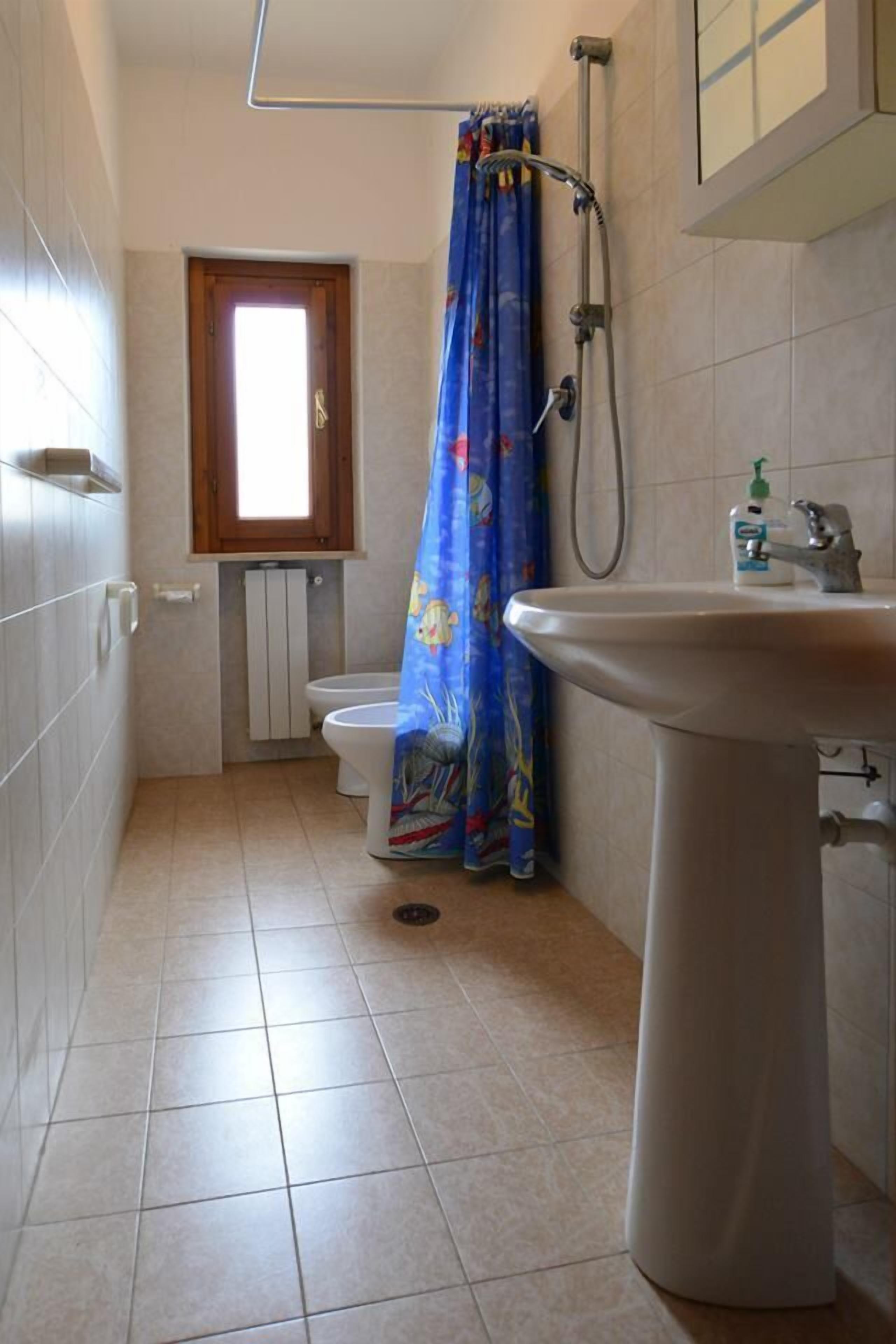 Une salle de bain comprenant des toilettes, un lavabo, une douche et une fenêtre.